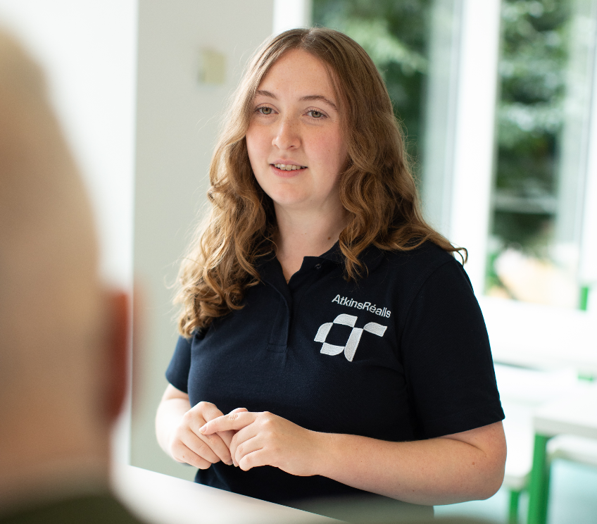 young woman wearing atkinsrealis branded tshirt talking to colleagues 